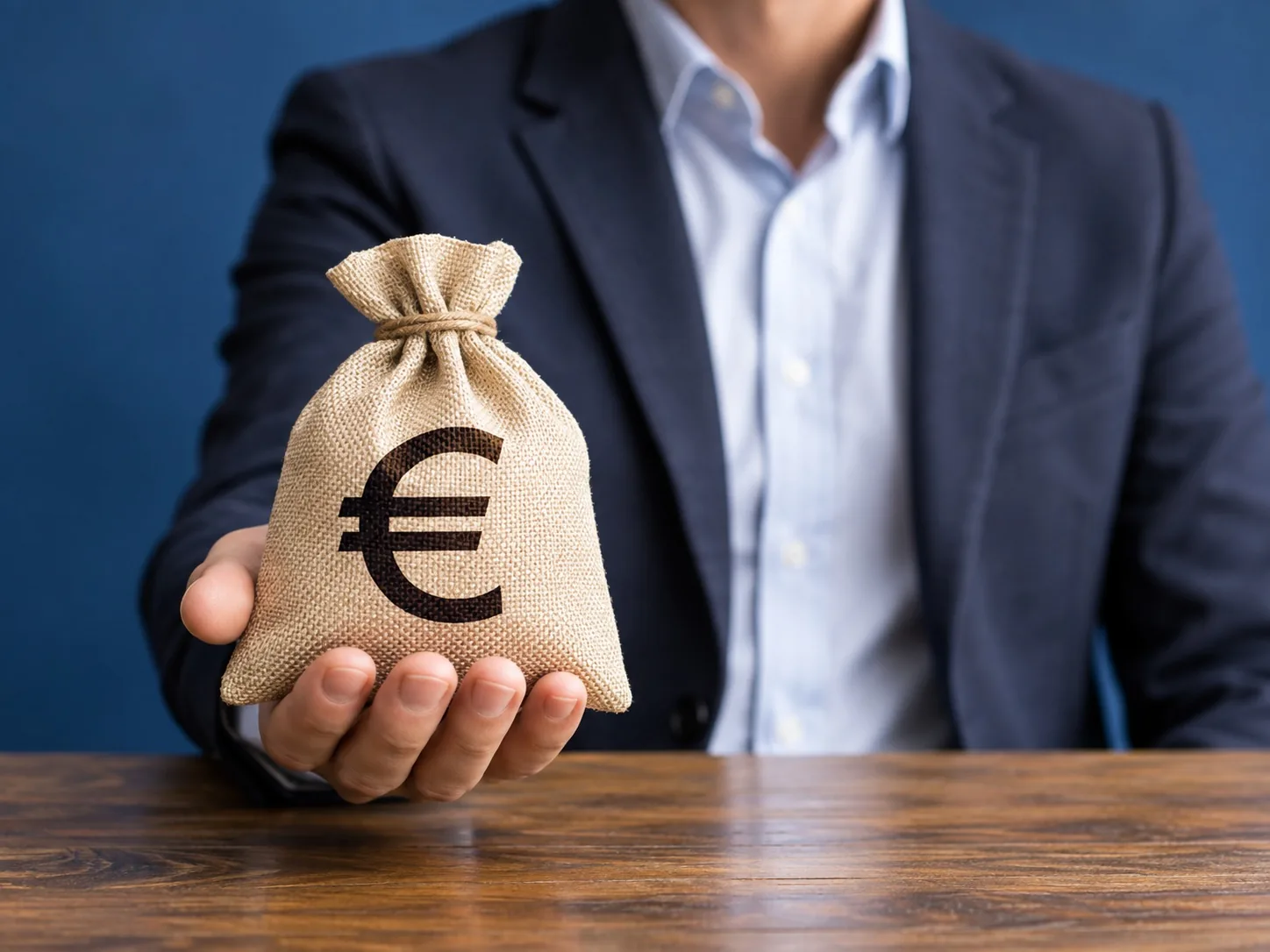 Man in pak houdt een geldzak met een euroteken in zijn hand
